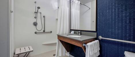 Un baño moderno con ducha, lavamanos, espejo e inodoro.
