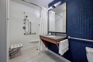 Un baño moderno con ducha, lavamanos, espejo e inodoro.
