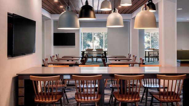 A conference room with a long table, multiple chairs, and pendant lighting.