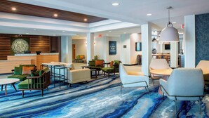 A modern lobby with a blue and white patterned carpet, seating areas, and a reception desk.
