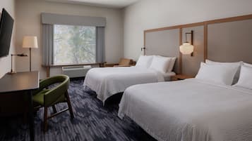 Habitación de hotel con dos camas, un escritorio, una silla, un televisor y una ventana con cortinas.