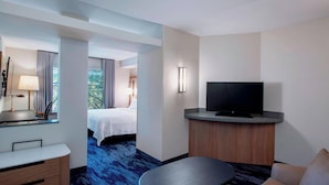 A hotel room with a bed, a desk, a television, and a view of the outdoors.