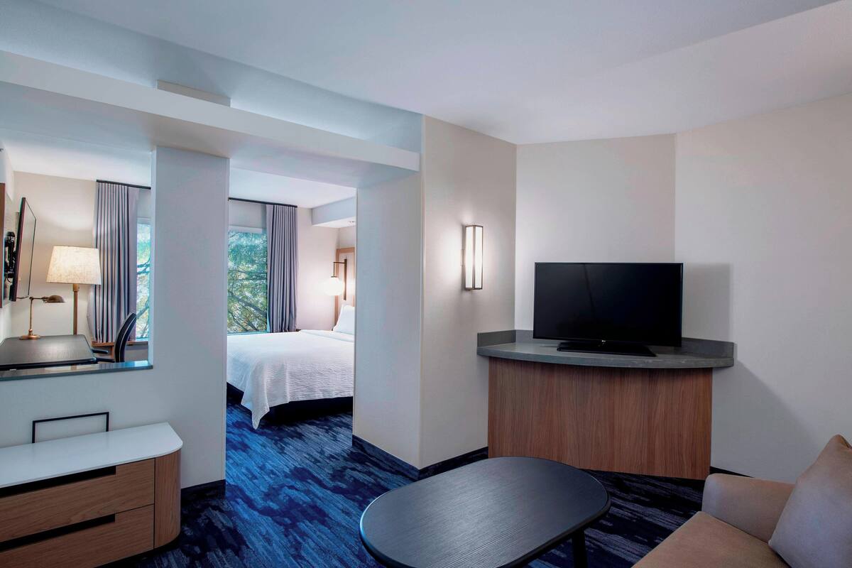 Une chambre d’hôtel équipée d’un lit, d’un bureau, d’une télévision et offrant une vue sur l’extérieur.