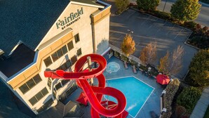 A hotel with a large indoor water slide, a swimming pool, and outdoor seating areas.