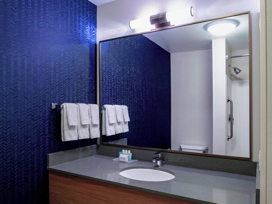 A bathroom with a large mirror, a sink, and a shower.