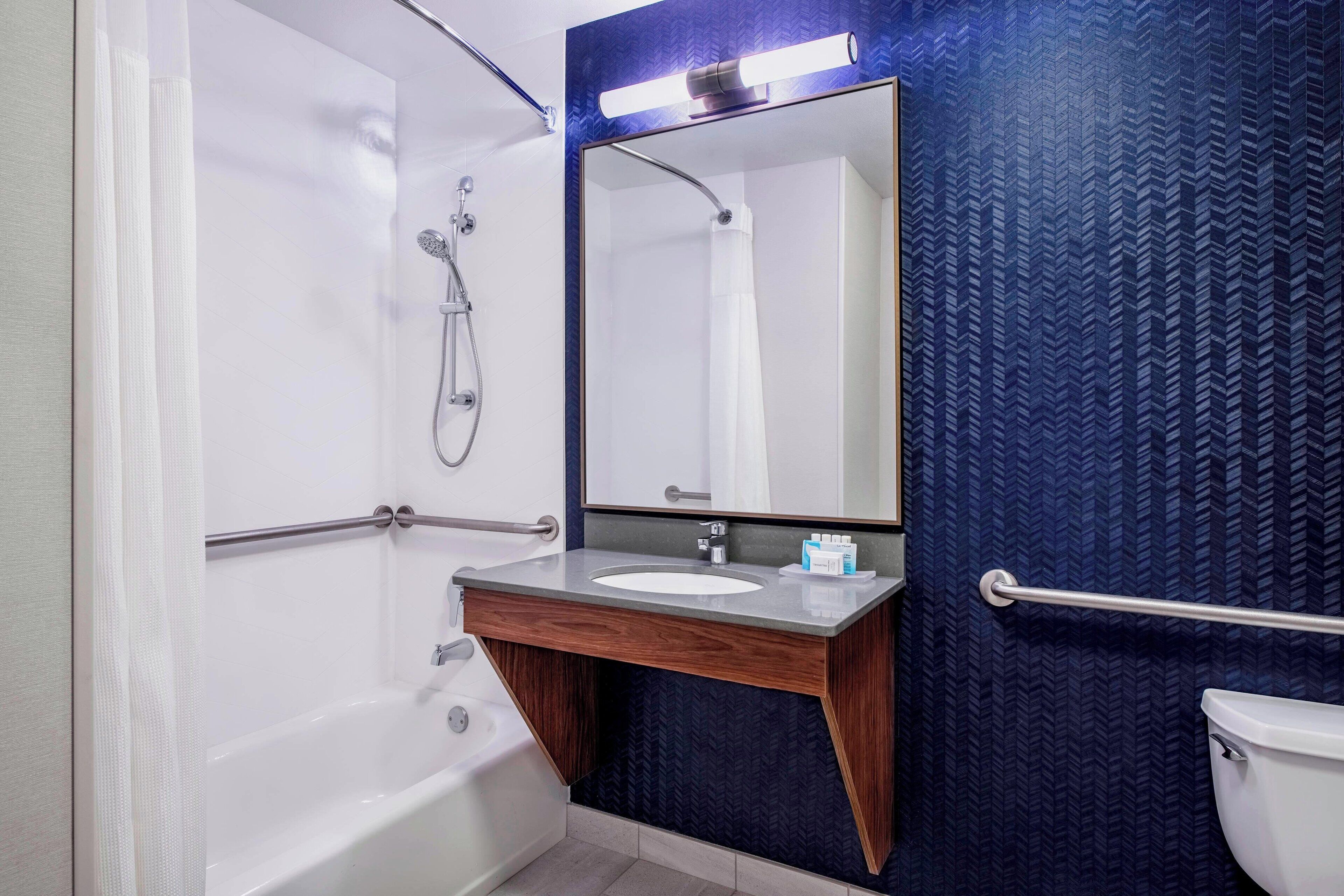 A bathroom with a bathtub, a sink, a mirror, and a toilet.