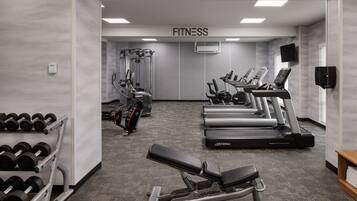 A fitness center with treadmills, weight machines, and dumbbells.