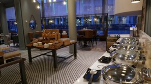 A hotel dining area with a buffet setup, including trays of food and silverware. - DoubleTree by Hilton Manchester - Piccadilly (Manchester)