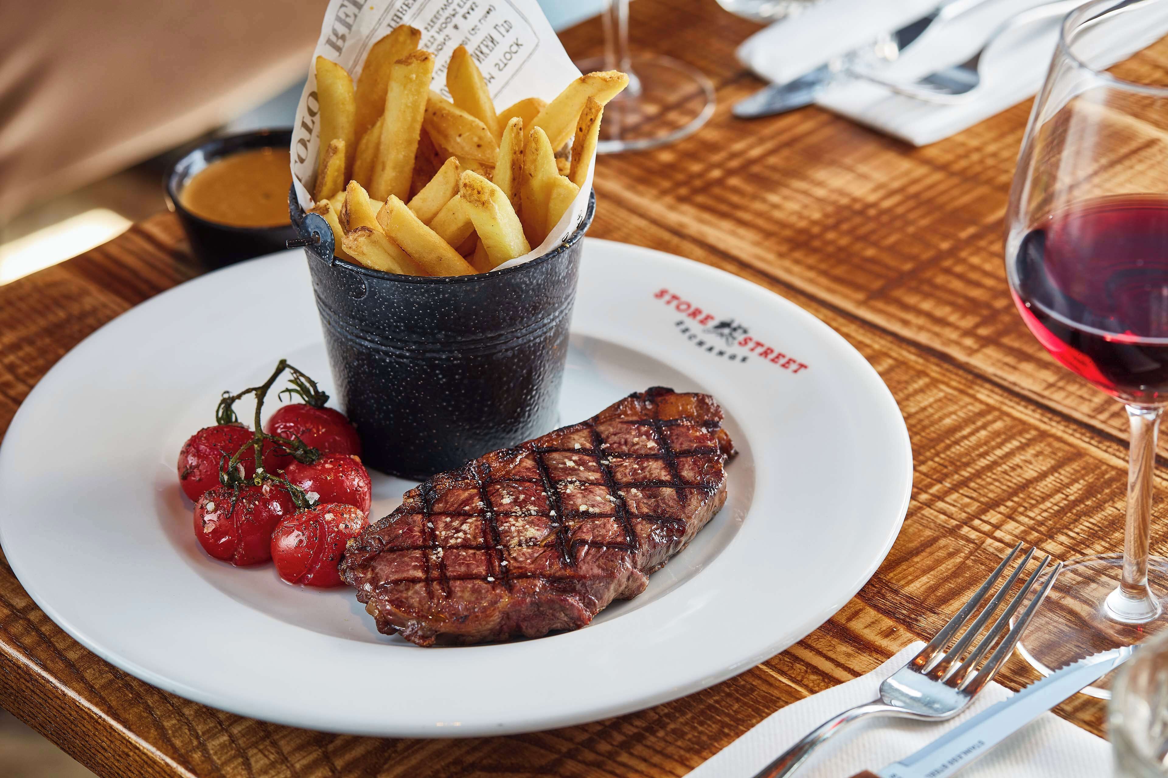 Um prato com bife, tomates cereja e batatas fritas.