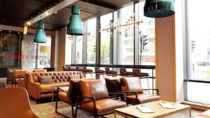 Un espace détente moderne avec des canapés et des fauteuils en cuir, une table basse en bois et des luminaires suspendus.