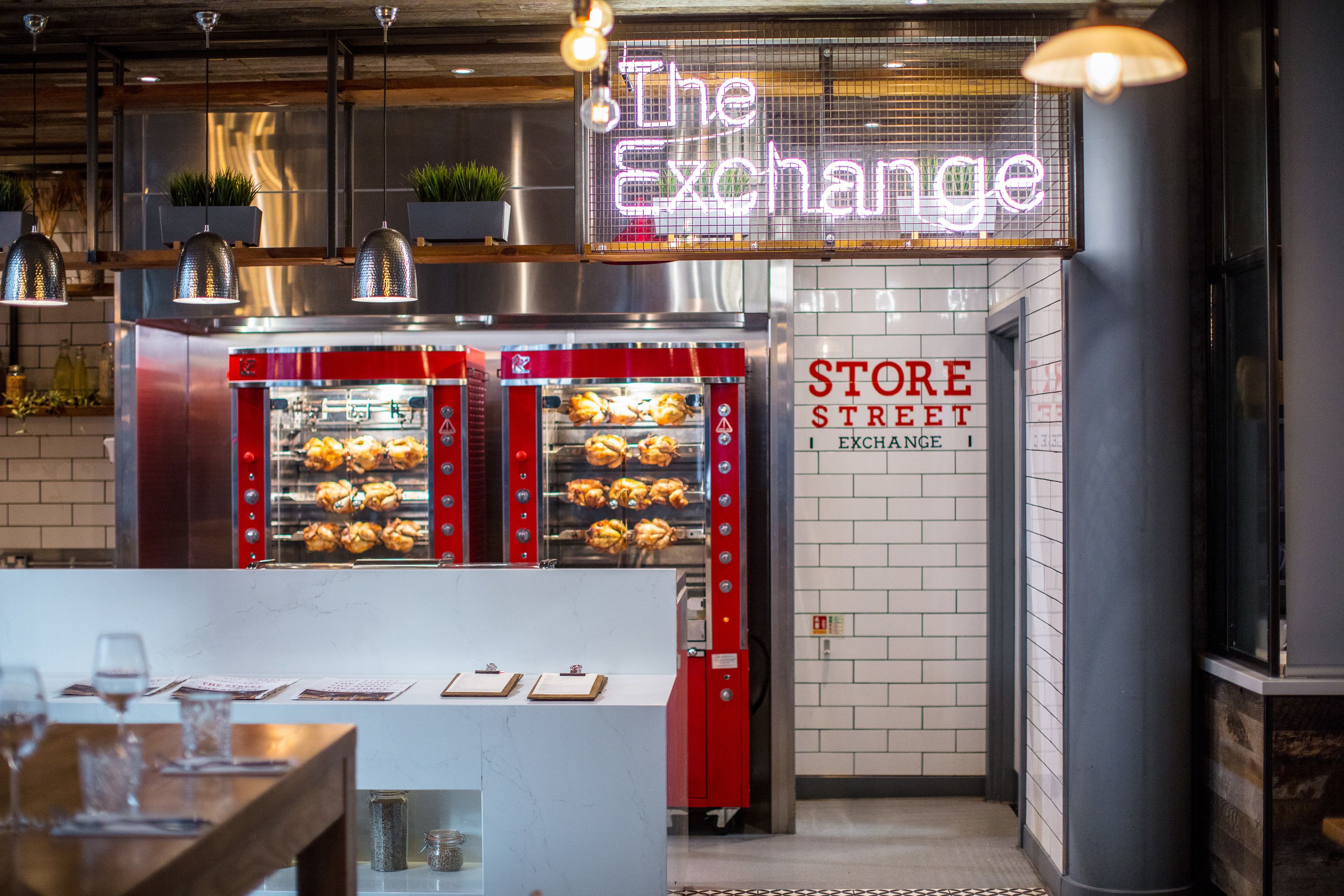 A restaurant with a neon sign reading "The Exchange," a red oven with baked goods, and a sign for "STORE STREET EXCHANGE."