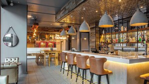 Un espace bar avec un comptoir, des tabourets et des suspensions lumineuses.