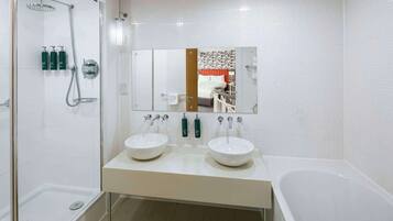A modern bathroom with two sinks, a shower, and a bathtub.