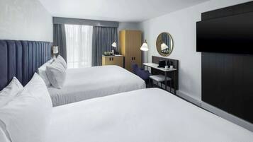 Een hotelkamer met twee bedden, een bureau, een stoel, een televisie en een kledingkast.