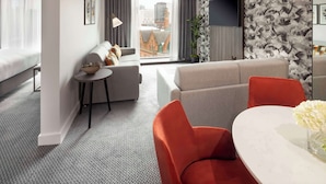 Une chambre d’hôtel moderne dotée d’une grande fenêtre, d’un canapé, d’une table à manger et d’un téléviseur.