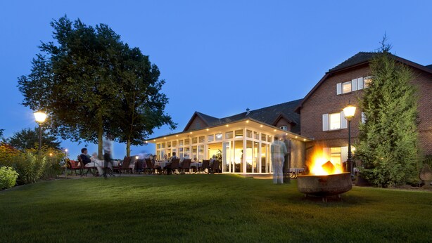 A building with a covered outdoor area, a lawn, and a fire pit. - Landhotel Bartmann (Sendenhorst)