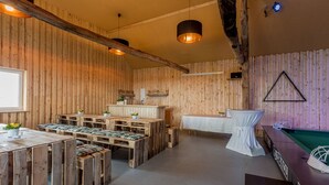A rustic wooden interior with a pool table, wooden tables and benches, and a bar area. - Landhotel Bartmann (Sendenhorst)