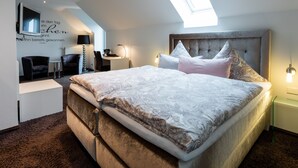 A modern bedroom with a large bed, a desk, and a chair. - Landhotel Bartmann (Sendenhorst)