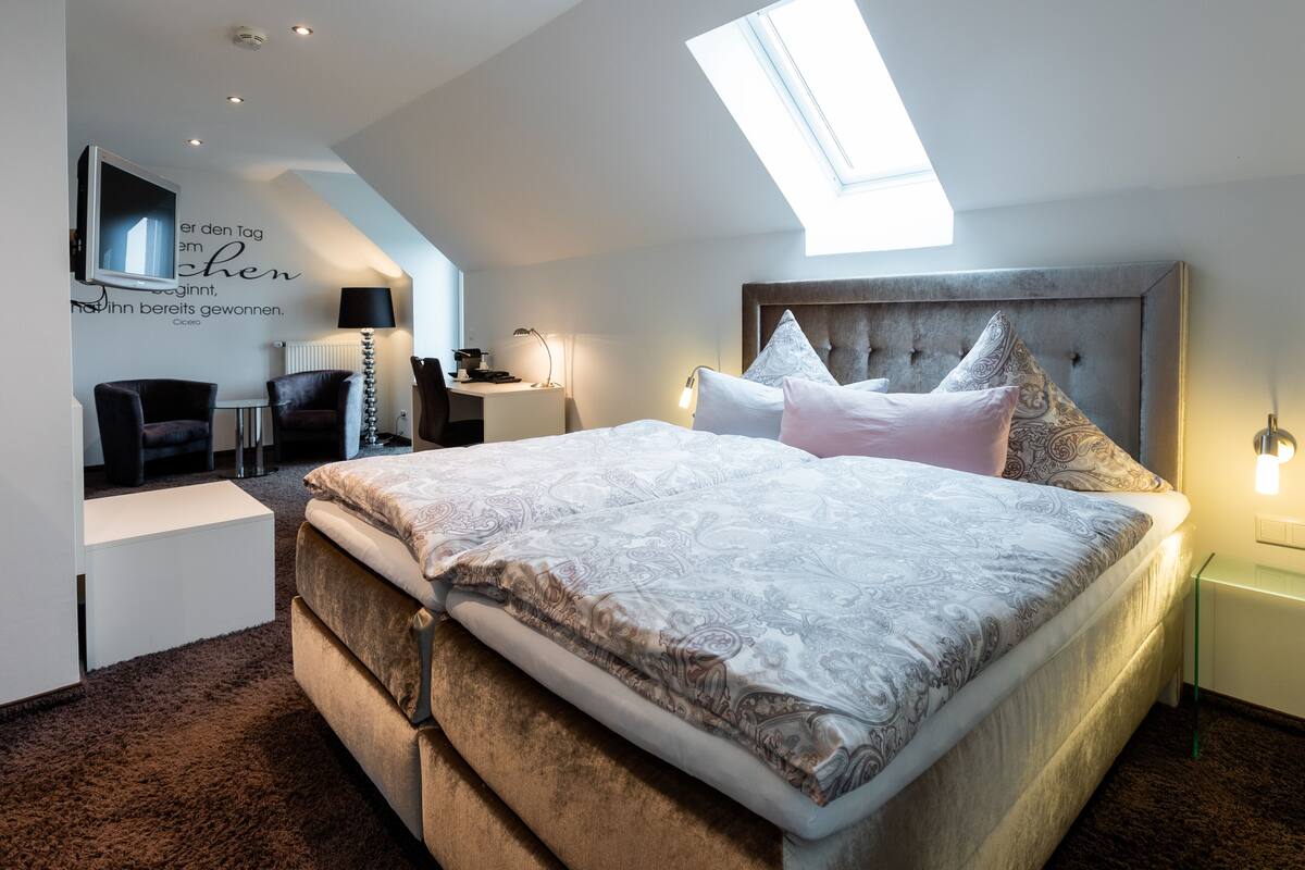 A modern bedroom with a large bed, a desk, and a chair.