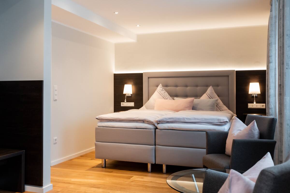 A modern bedroom with a large bed, bedside tables, a sofa, and a TV.