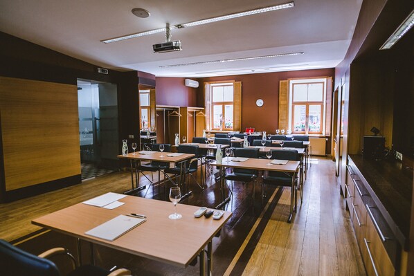 A conference room with tables, chairs, and a projector.