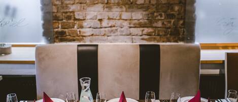 A restaurant setting with a brick wall, a booth, and a table set for a meal.