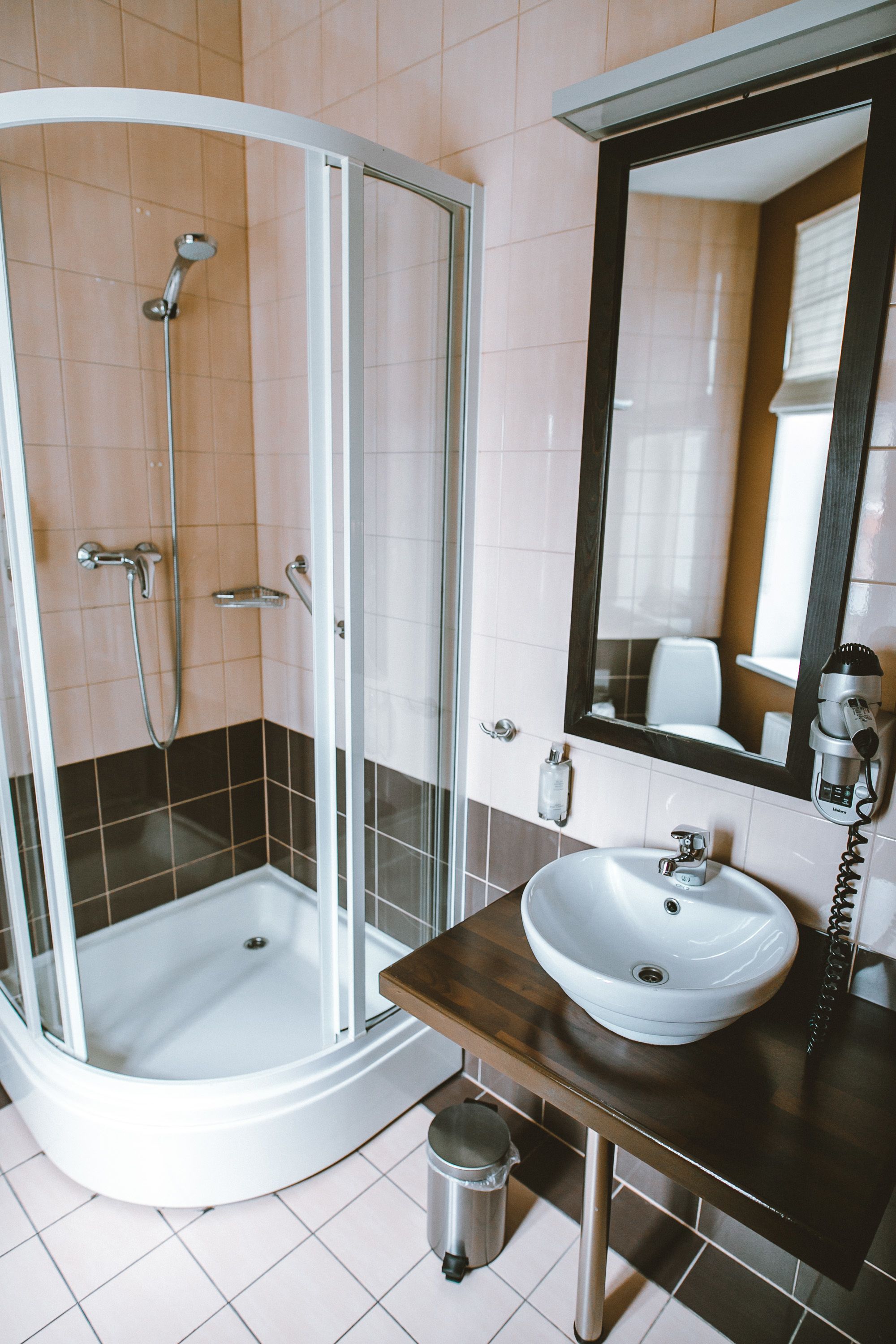 Un baño con ducha, lavamanos y espejo.