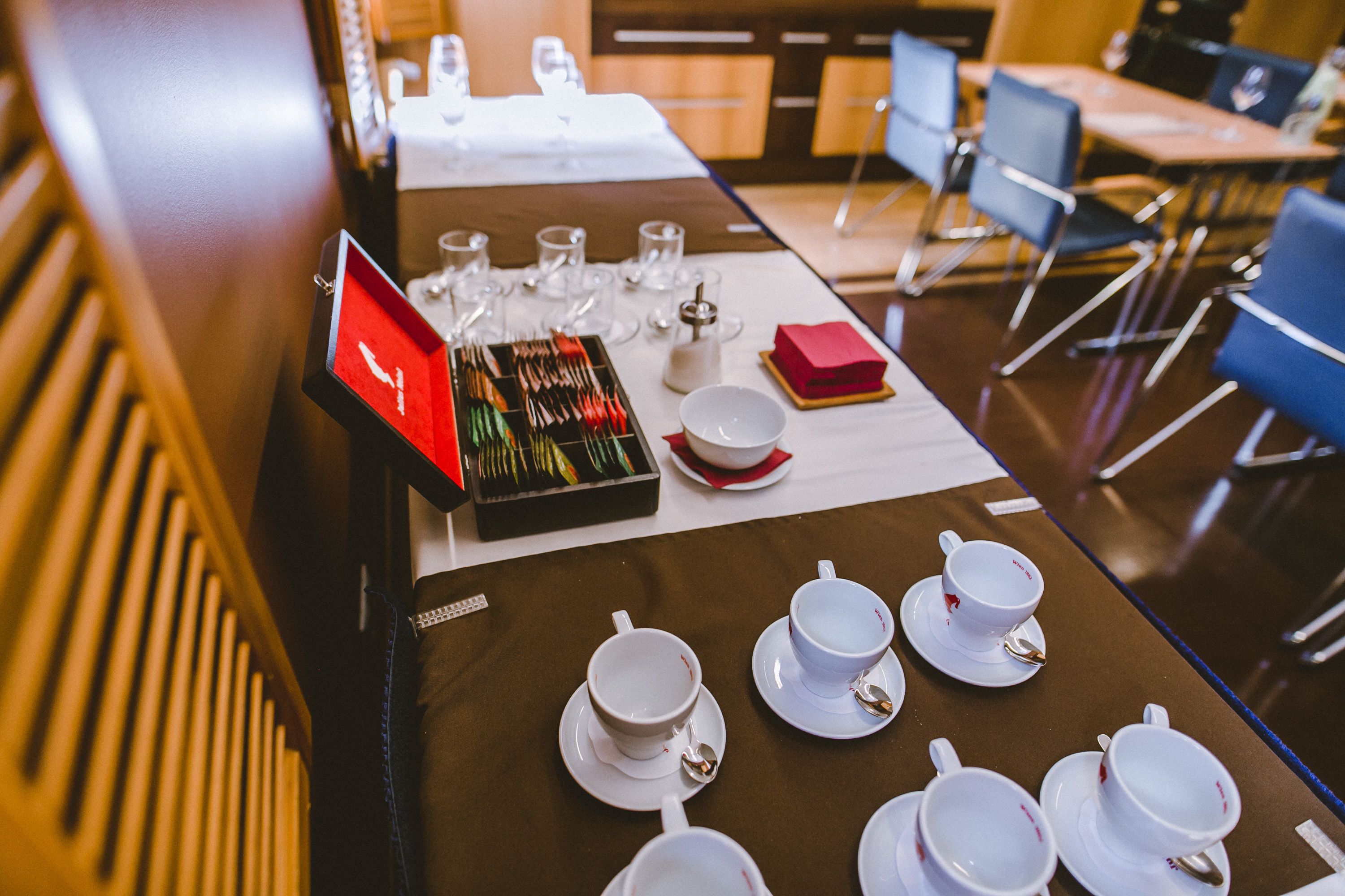 A hotel dining area with tables set for tea service, including teapots, cups, saucers, and spoons.