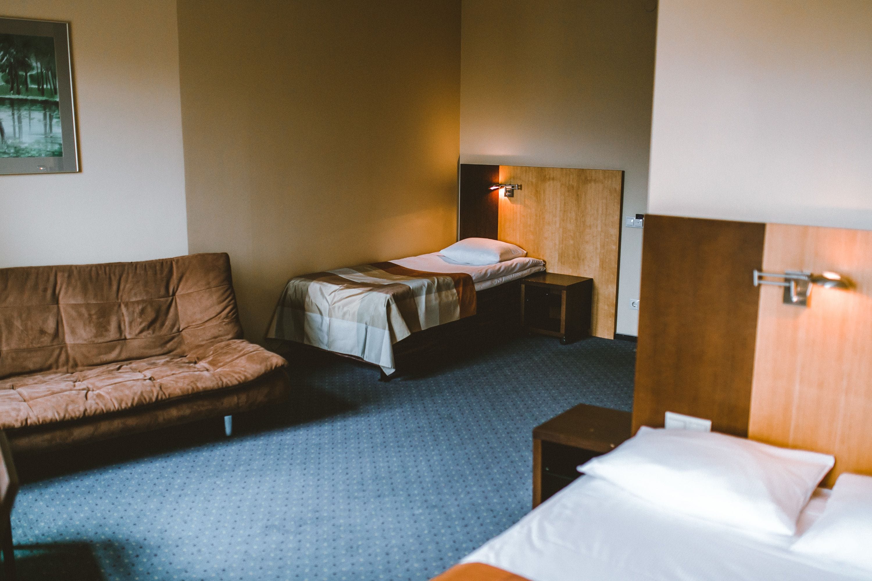 Hotellihuone, jossa on yksi sänky, sohva, pieni pöytä ja yöpöytä.