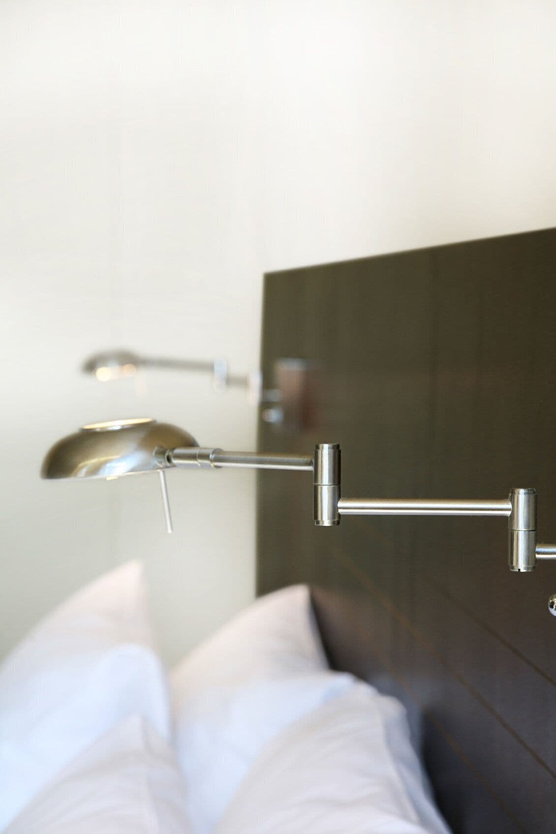 A modern bathroom with a dark headboard, a wall-mounted faucet, and a towel rack.
