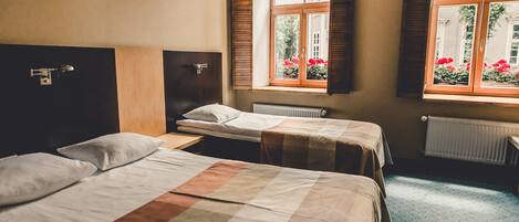 Una habitación de hotel con dos camas, una ventana con persianas de madera y un radiador.