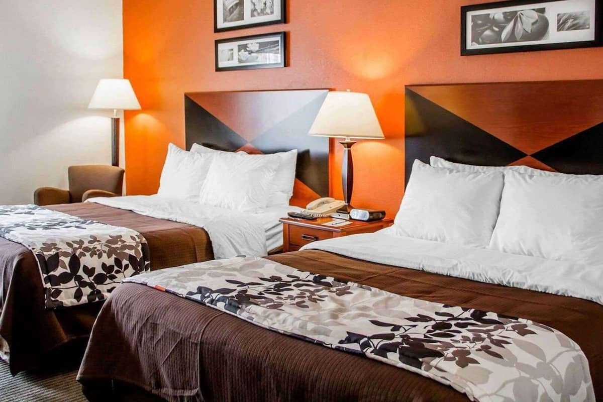 Una habitación de hotel con dos camas, una mesita de noche con teléfono y cuadros en la pared.