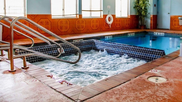 En swimmingpool med en stege, kaklade väggar och en livboj.