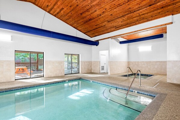 An indoor swimming pool with a wooden ceiling, clear glass doors, and a tiled floor. - La Quinta Inn & Suites by Wyndham Boone University (Boone)