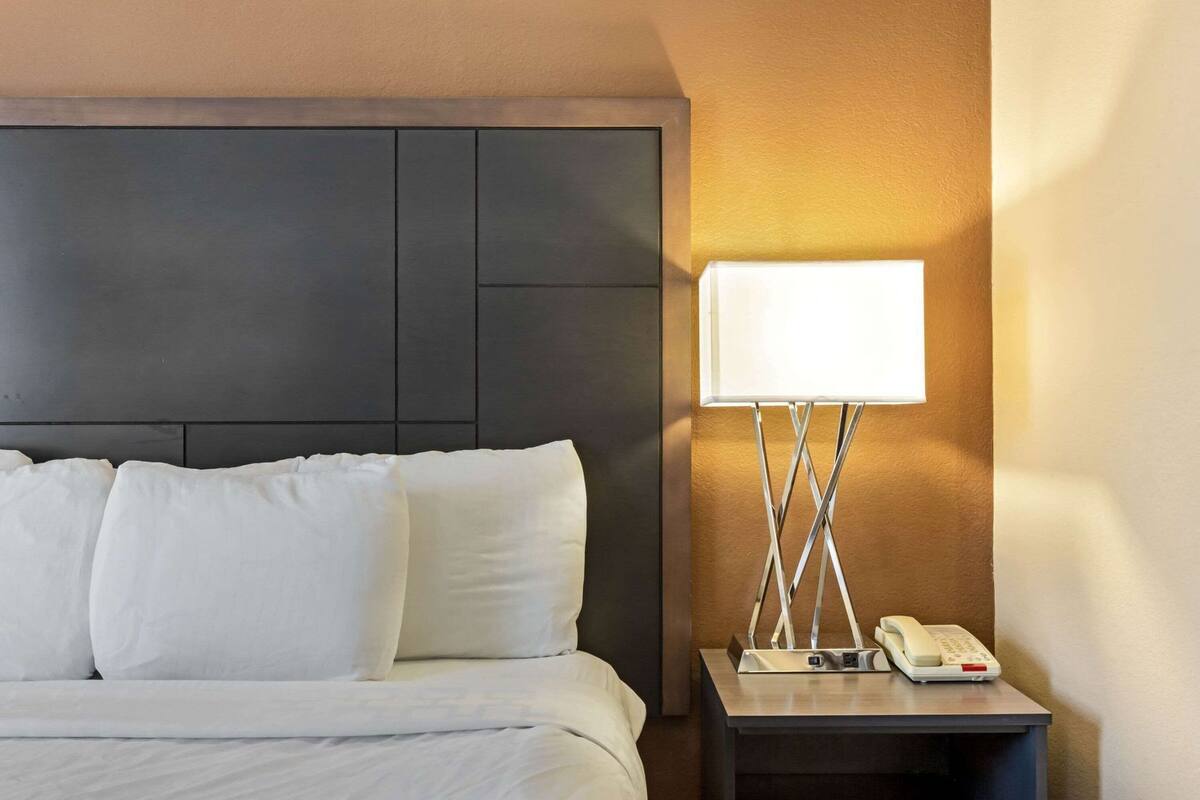 A hotel room with a bed, a bedside table with a lamp, and a telephone.