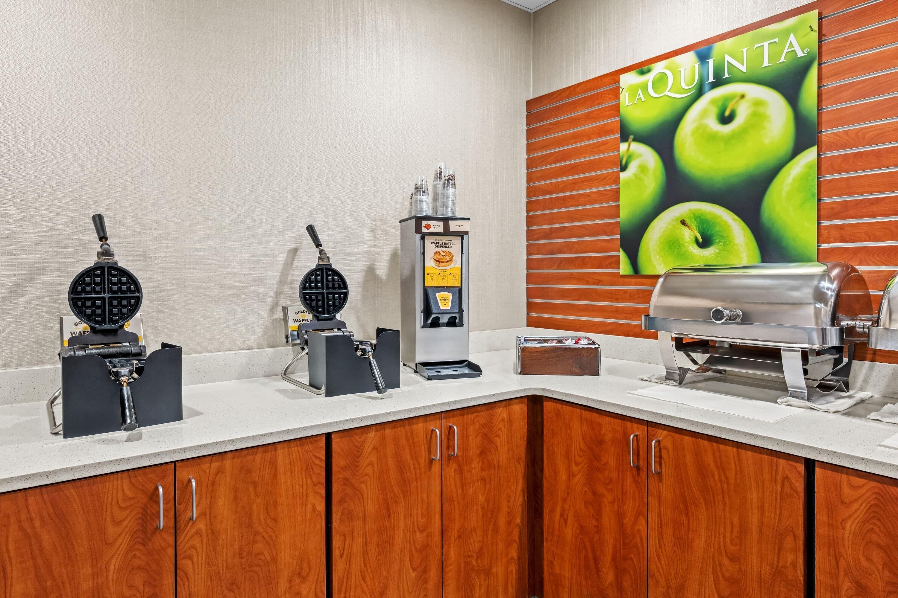 A kitchenette with waffle makers, a waffle dispenser, and a grill.