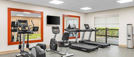 Un gimnasio con cintas de correr, elípticas y una bicicleta estática.