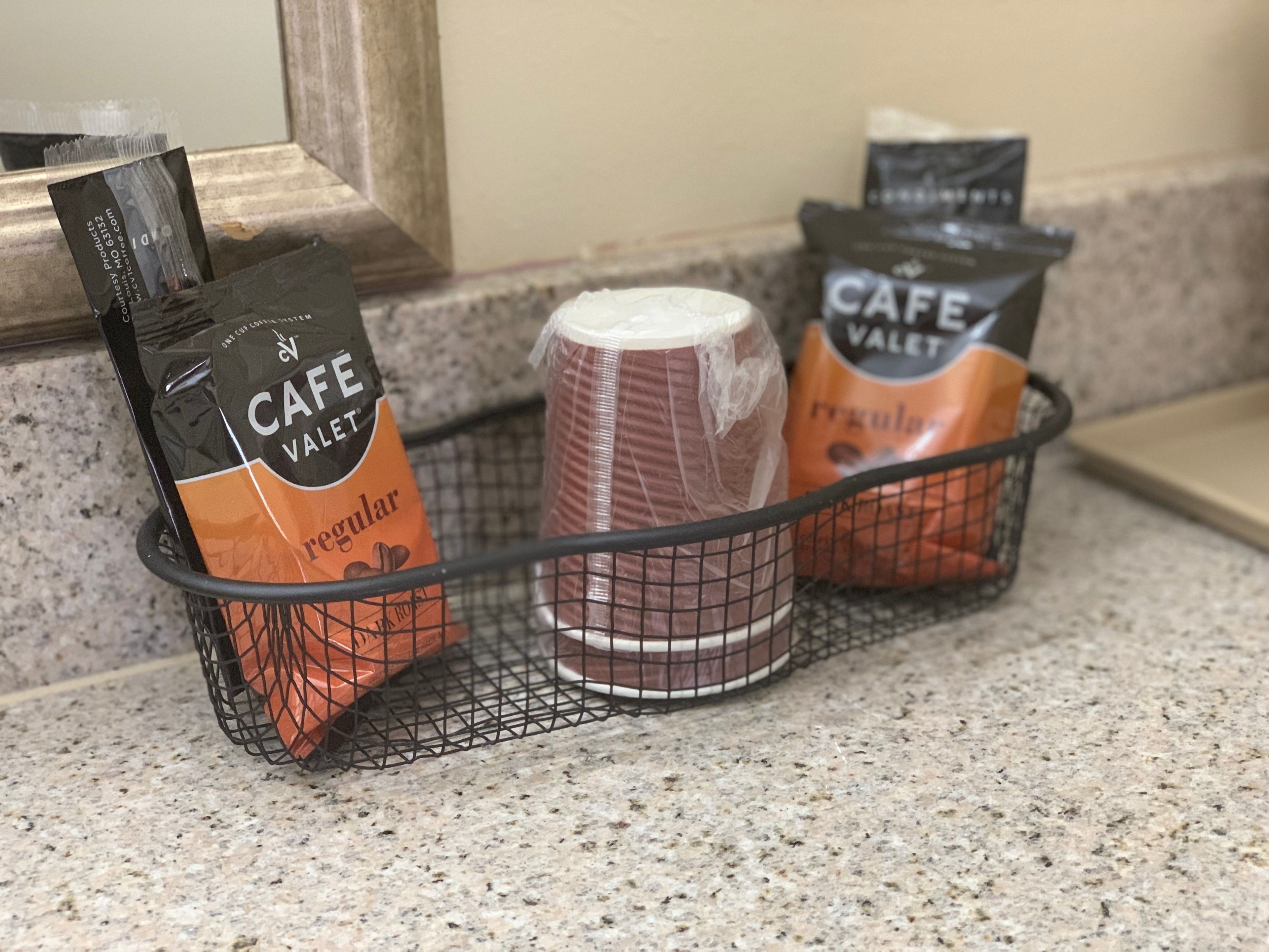 Una cesta con tres bolsas de café Cafe Valet sobre una encimera de cocina.