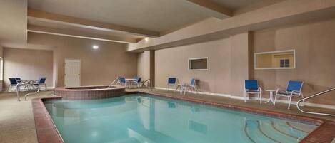 Une piscine intérieure avec des chaises bleues et une porte.