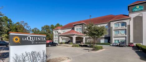 A La Quinta hotel with a large parking lot, multiple buildings, and a clear blue sky.