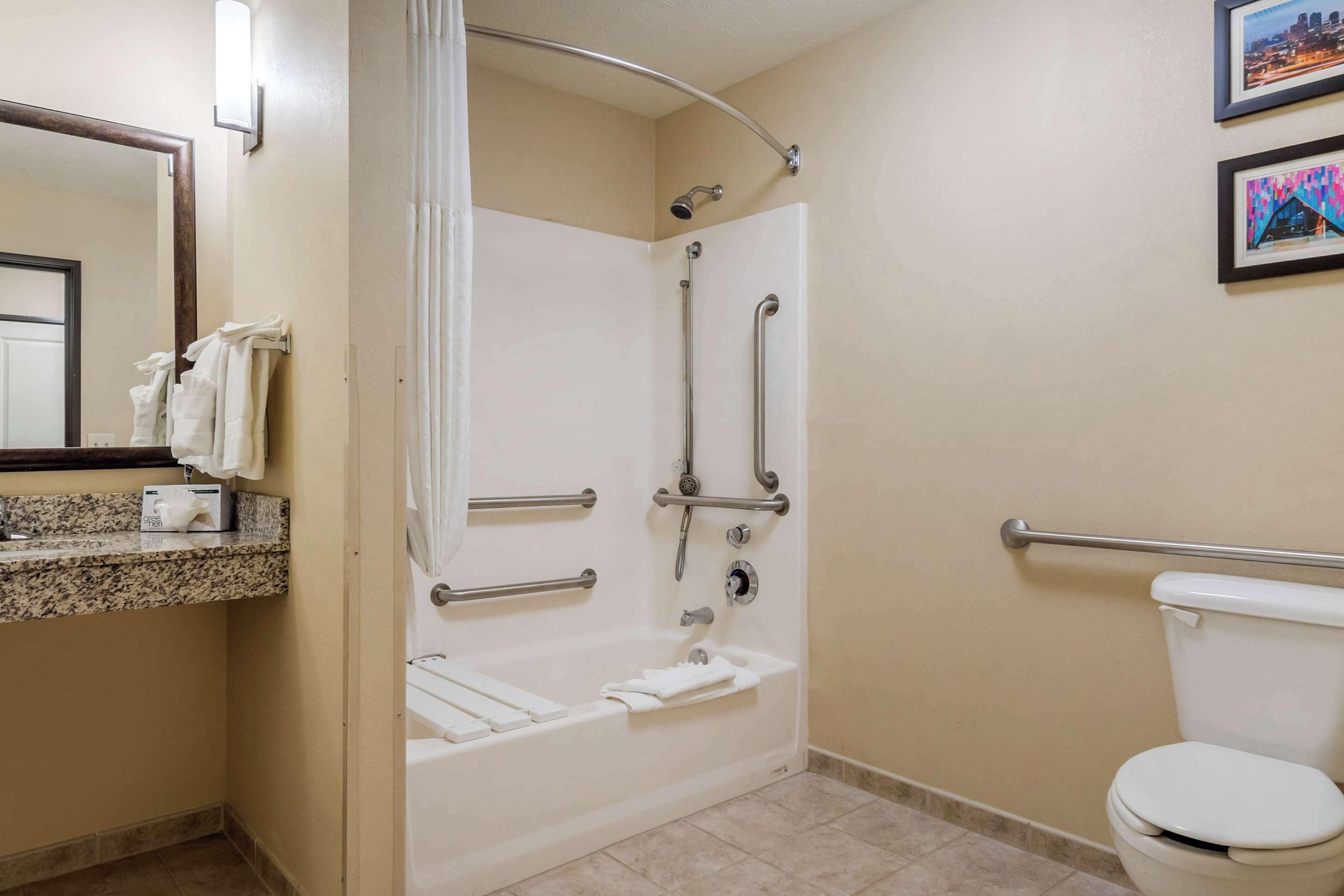Un baño con ducha, inodoro e lavamanos con barra para toallas.