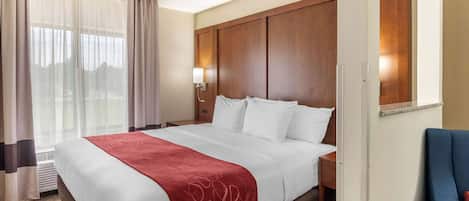 A hotel room with a large bed, a wooden headboard, a desk, and a chair.