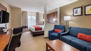 Een hotelkamer met een bed, een bureau met stoel, een bank en een televisie.