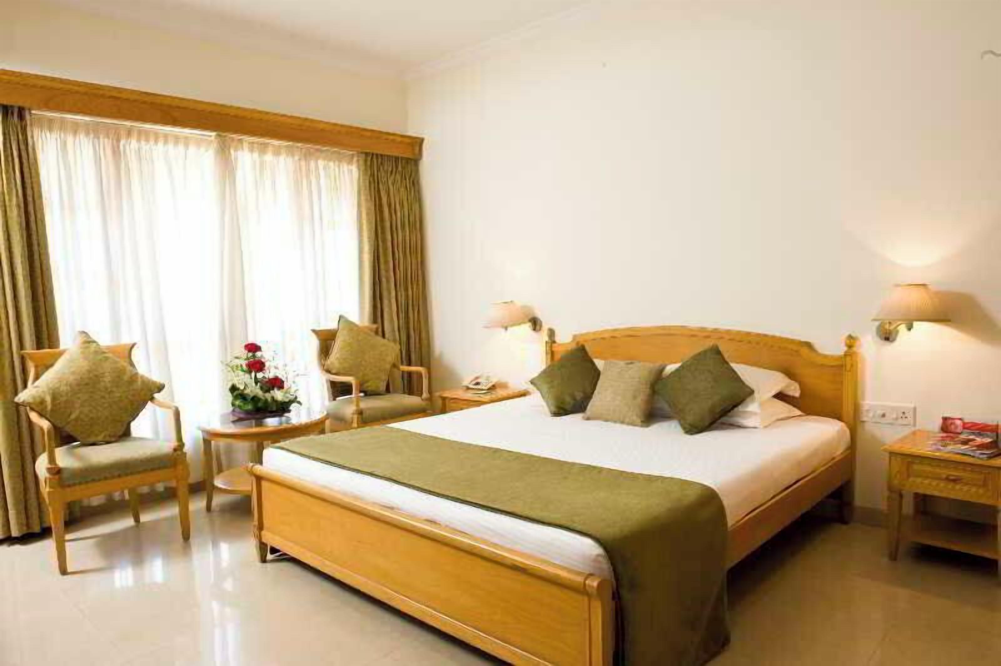 A hotel room with a wooden bed, two bedside tables, a chair, and a nightstand.