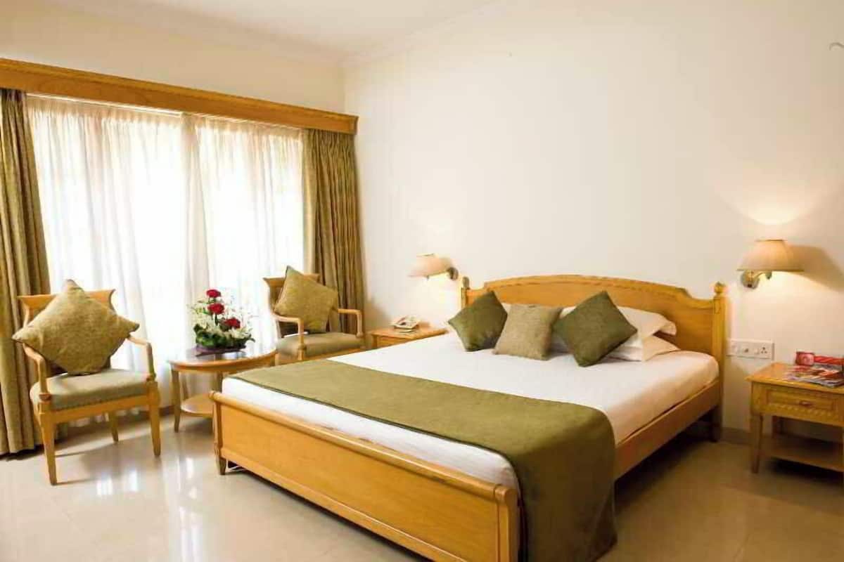 A hotel room with a wooden bed, two bedside tables, a chair, and a nightstand.