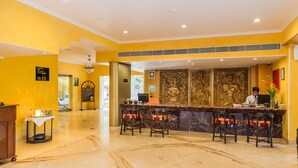 Zona de recepció d'hotel amb sòl de marbre, mostrador de recepció i espai d'estar amb cadires.