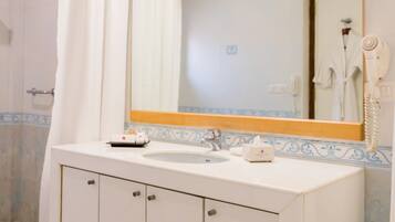 A bathroom with a white sink, a mirror, and a shower area.