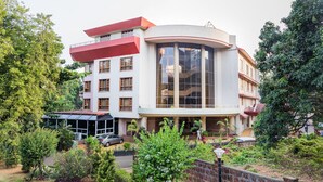 Un edifici de diverses plantes amb façana de vidre corbat, envoltat de vegetació abundant i un camí de maó.