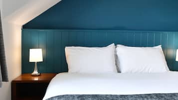 A hotel room with a bed, a nightstand, a lamp, and a blue headboard.