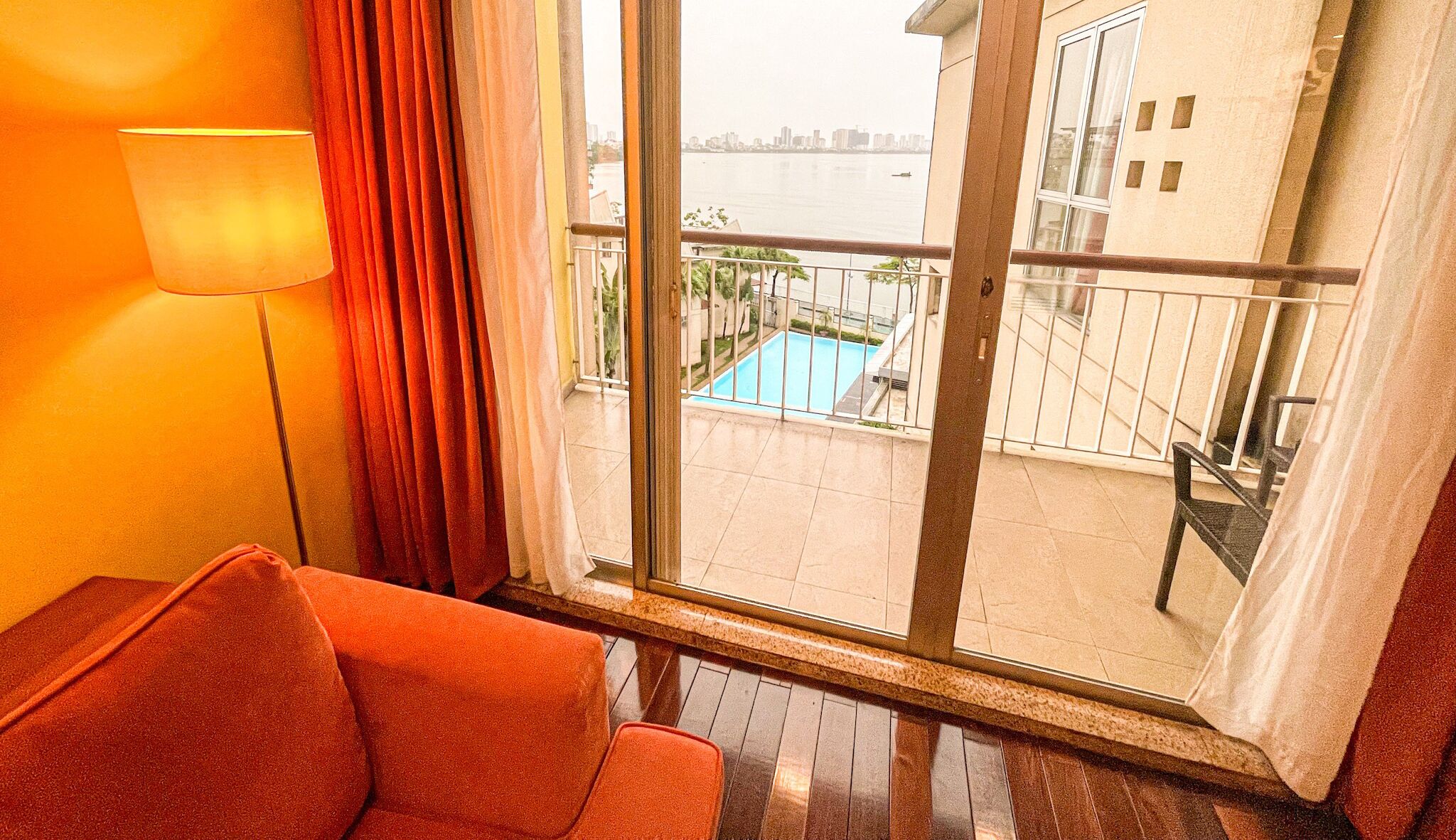Habitación de hotel con vista a una piscina y al horizonte de la ciudad.